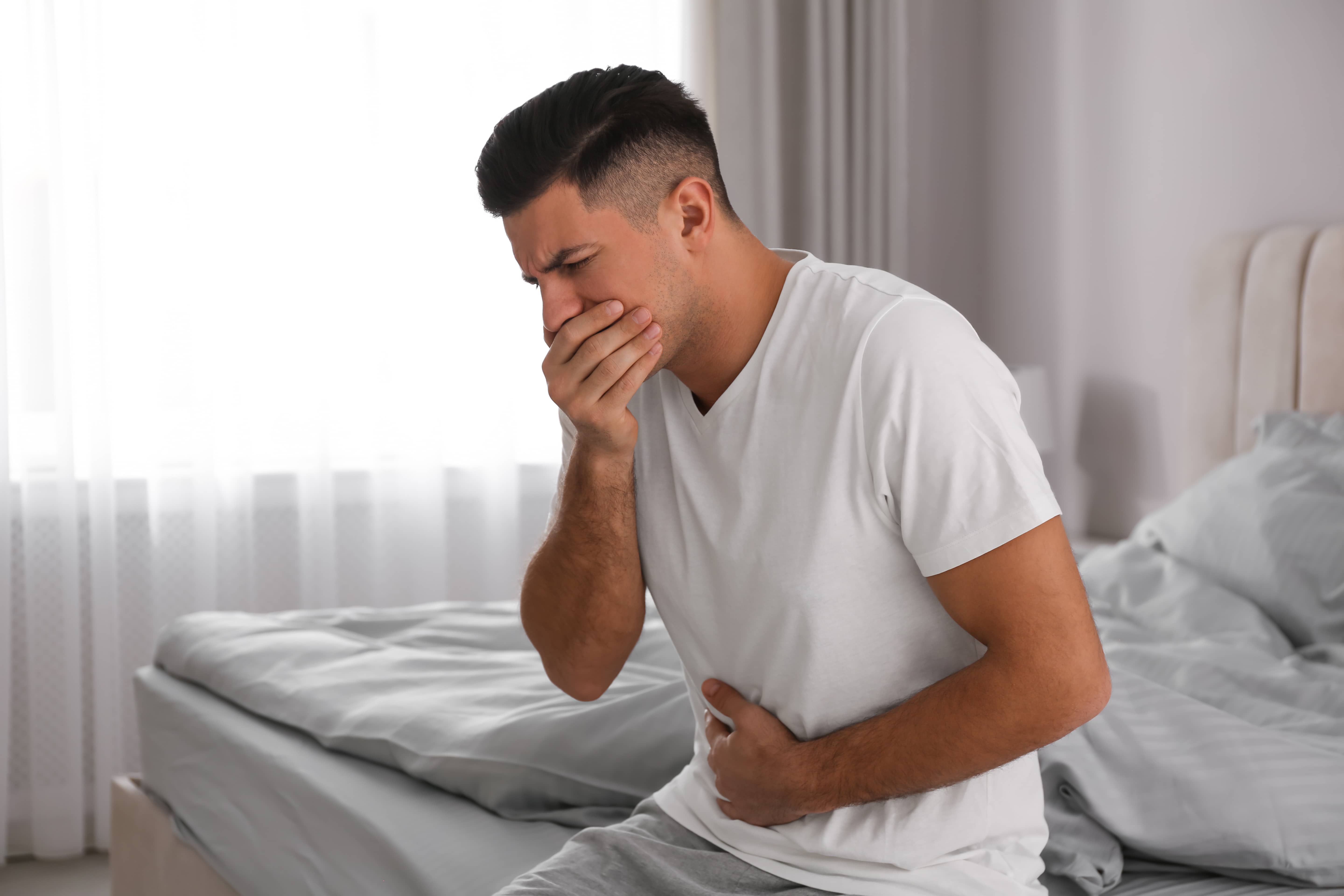 Man experiencing nausea and stomach discomfort from Norovirus gastroenteritis while traveling in Japan