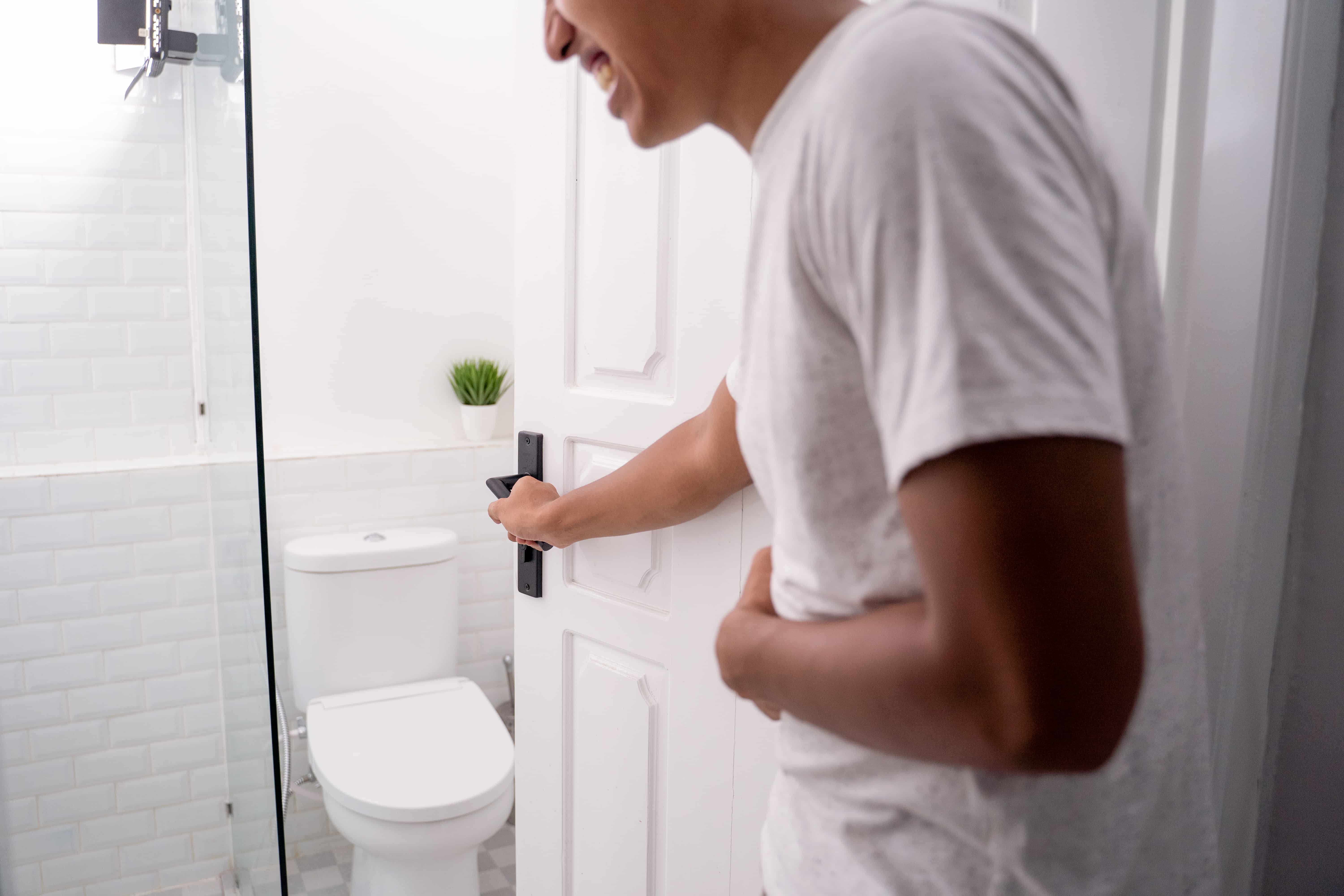 Man urgently walking towards bathroom due to frequent urination, a common UTI symptom